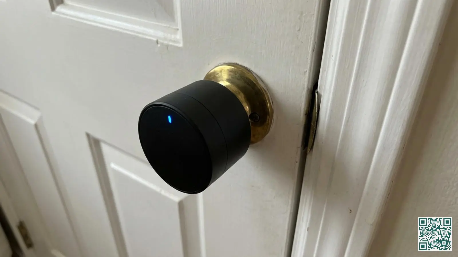 Zwart retrofit smart lock apparaat gemonteerd aan de binnenzijde van een deur op een bestaand cilinderslot met LED indicator